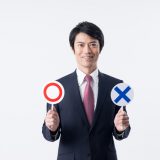 ○と✕を持った男性