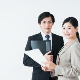 書類を持ったスーツ姿の男女